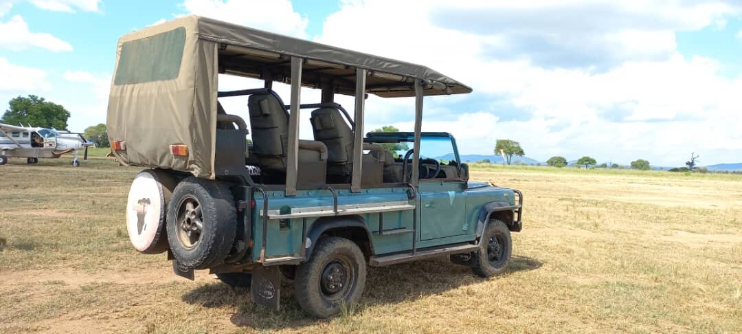 Open sided game drive vehicle parked on the airstrip in Mikumi
