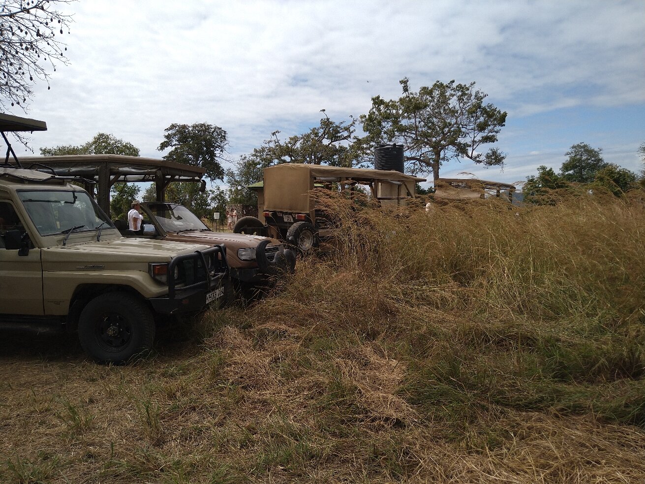 Two safari vehicles parked beside thatched rest huts in Mikumi National Park