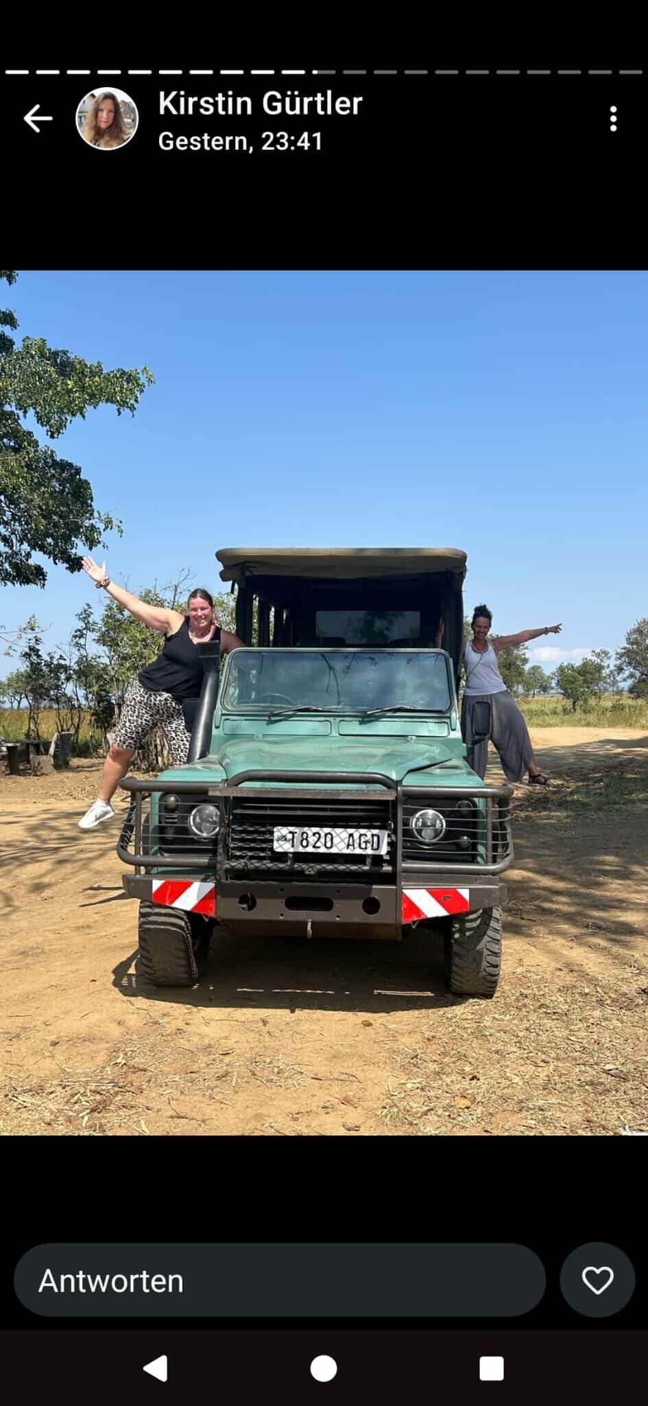 Two women posing at a green Land Rover safari truck in Mikumi National Park