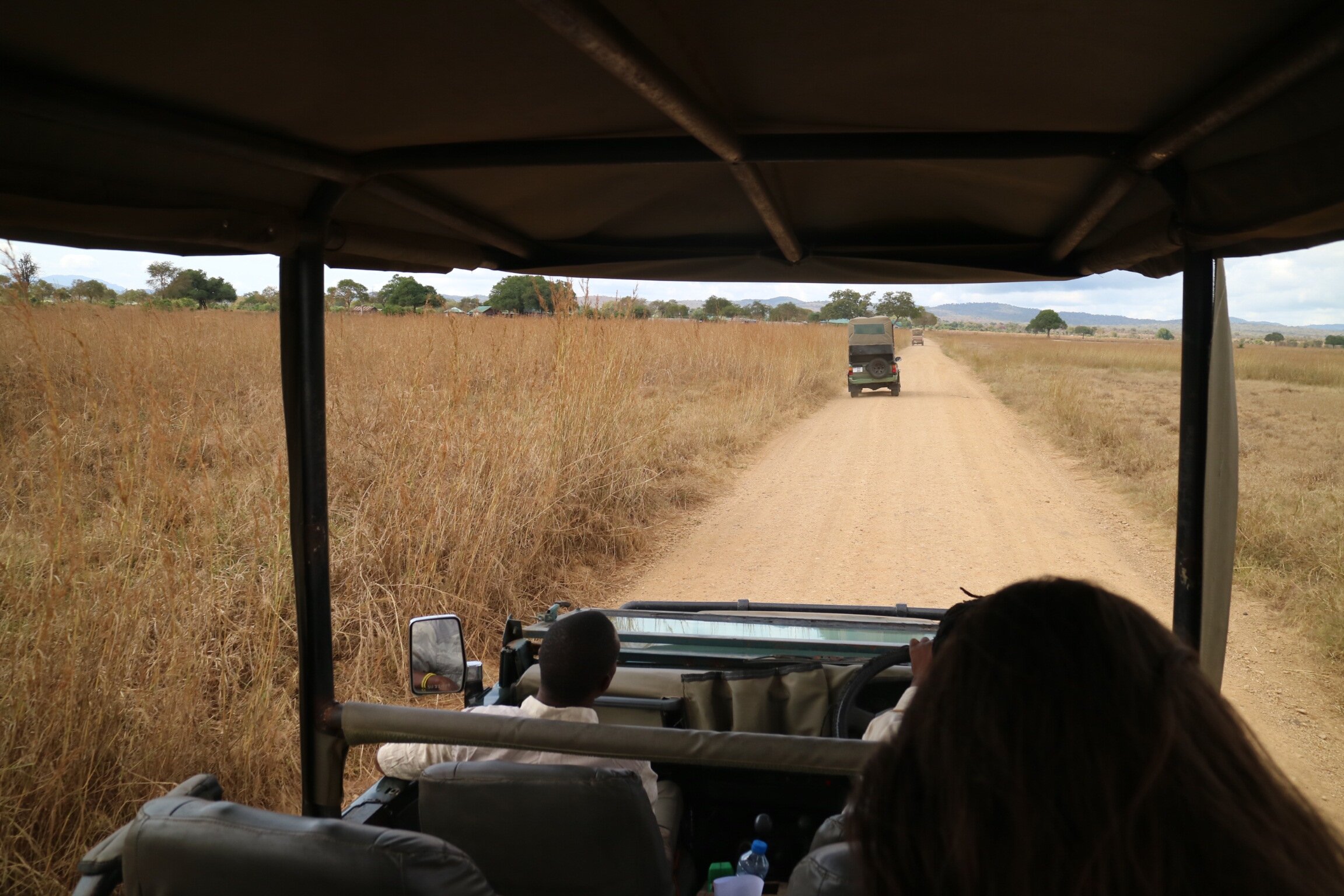 View from a safari vehicle following another along a dirt track in Mikumi
